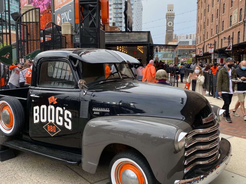 Pit beef stand inside of camden Yards with a vintage car with the name boogs on it
